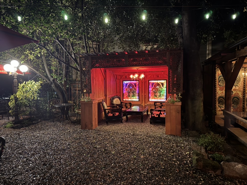 Illuminated blue lanterns hang under a pergola at dusk, creating a warm, inviting ambiance.